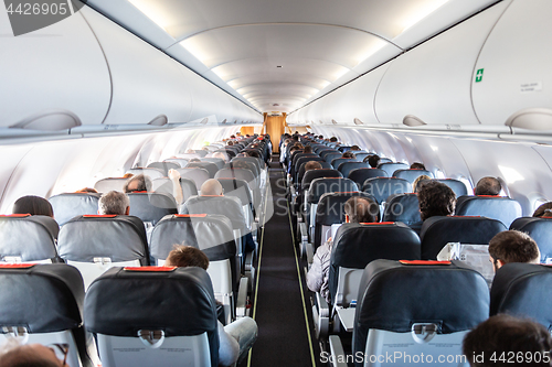 Image of Interior of commercial airplane with passengers on their seats during flight.