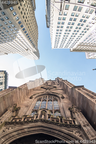 Image of Wide angle upward view of Trinity Church at Broadway and Wall Street with surrounding skyscrapers, Lower Manhattan, New York City, USA