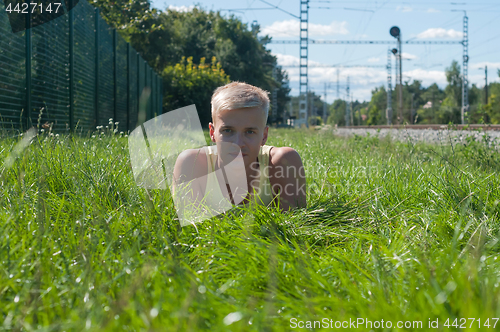 Image of Young man in yellow t-shirt sitting on the green grass