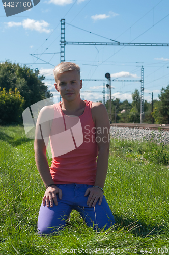 Image of Young man in orange sitting on the green grass