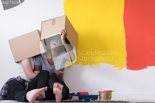 Image of young multiethnic couple playing with cardboard boxes