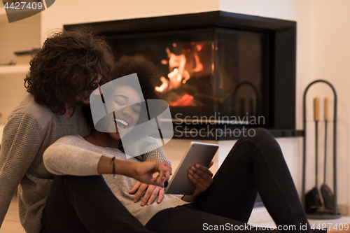Image of multiethnic couple using tablet computer on the floor