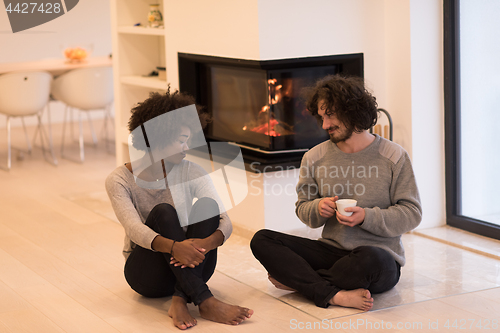 Image of multiethnic couple  in front of fireplace