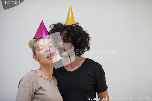 Image of couple in party hats blowing in whistle