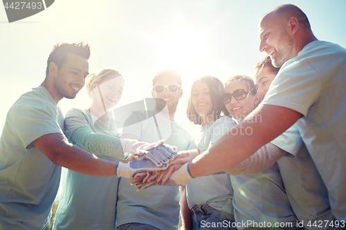 Image of group of volunteers putting hands on top outdoors