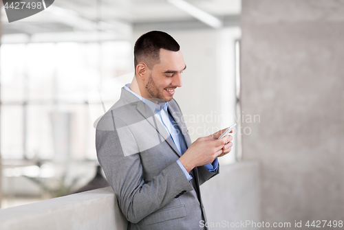 Image of smiling businessman with smarphone at office