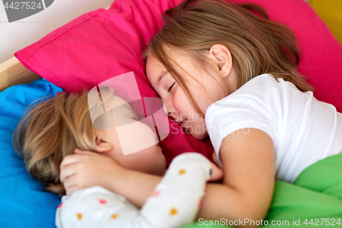 Image of happy little girls sleeping in bed at home