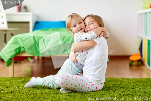 Image of happy little girls or sisters hugging at home