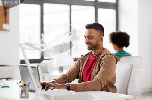 Image of happy indian man with laptop computer at office