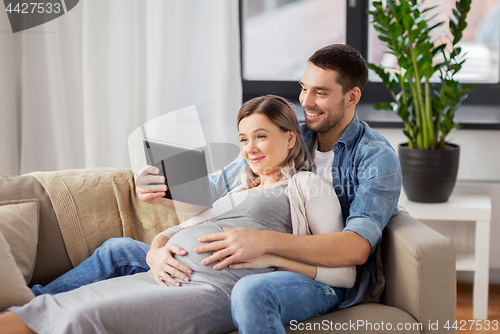 Image of man and pregnant woman with tablet pc at home