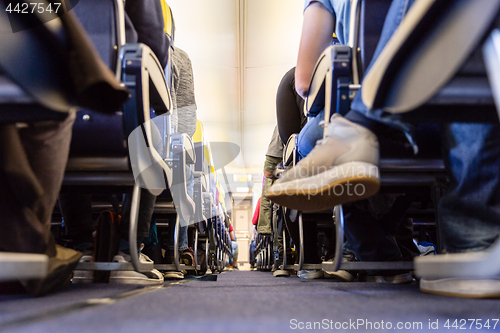 Image of Low agle view of passenegers commercial airplane aisle with passenegers sitting on their seats while flying