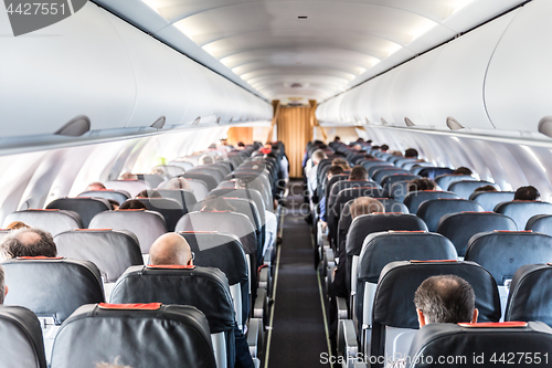 Image of Interior of commercial airplane with passengers on their seats during flight.