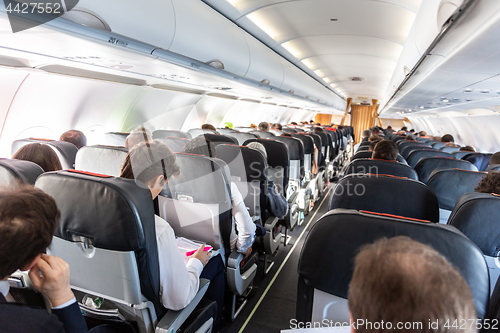 Image of Interior of commercial airplane with passengers on their seats during flight.