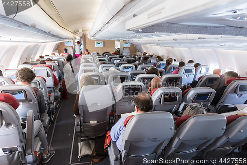 Image of Interior of large commercial airplane with passengers on their seats during flight.