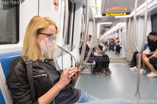 Image of Young girl reading from mobile phone screen in metro.