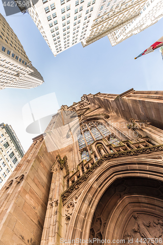 Image of Wide angle upward view of Trinity Church at Broadway and Wall Street with surrounding skyscrapers, Lower Manhattan, New York City, USA