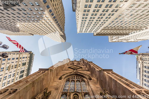 Image of Wide angle upward view of Trinity Church at Broadway and Wall Street with surrounding skyscrapers, Lower Manhattan, New York City, USA