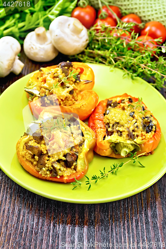 Image of Pepper stuffed with mushrooms and couscous in plate on wood