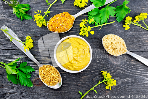 Image of Mustard different in bowl and spoons on black board top