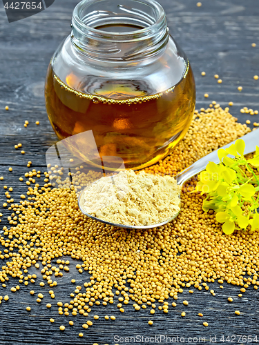 Image of Mustard powder in spoon with oil and flower on board