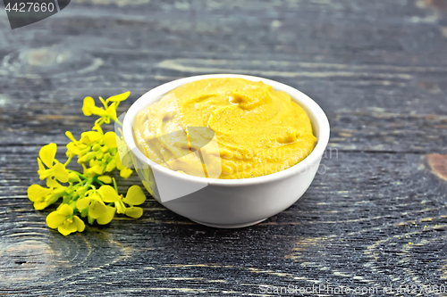 Image of Sauce mustard in bowl with flower on dark board