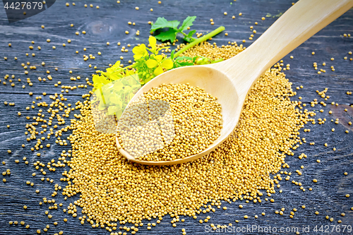 Image of Mustard seeds in wooden spoon with flower on board