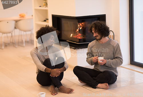 Image of multiethnic couple  in front of fireplace