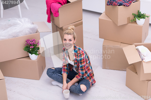 Image of woman with many cardboard boxes sitting on floor