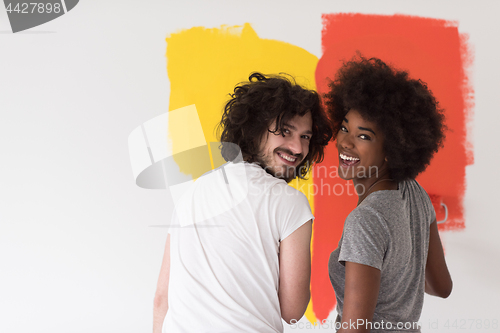 Image of multiethnic couple painting interior wall