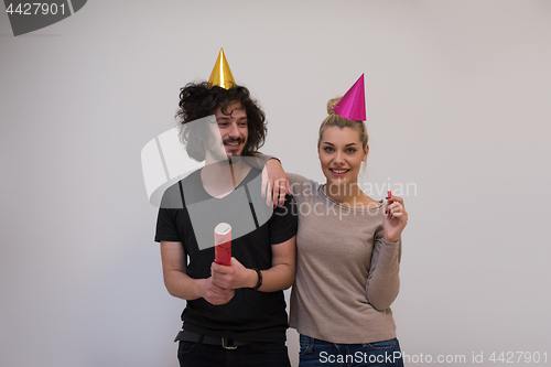 Image of couple in party hats blowing in whistle