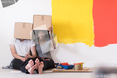 Image of young multiethnic couple playing with cardboard boxes