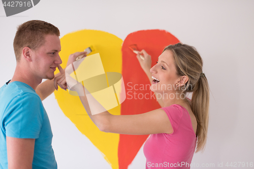 Image of couple are painting a heart on the wall