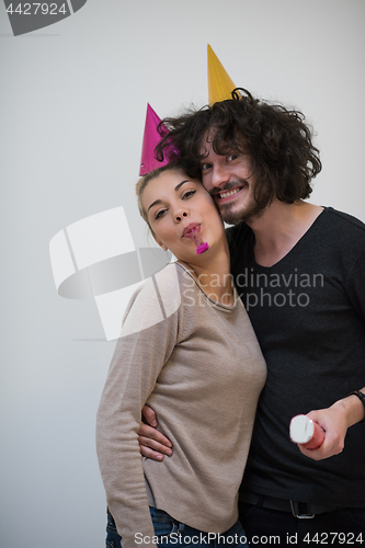 Image of couple in party hats blowing in whistle