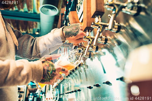 Image of Hand of bartender pouring a large lager beer in tap.