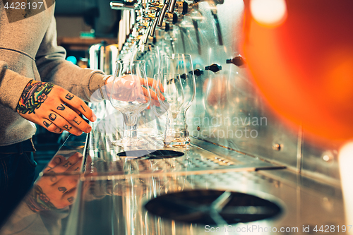 Image of Hand of bartender pouring a large lager beer in tap.