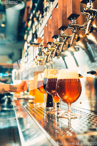 Image of Hand of bartender pouring a large lager beer in tap.