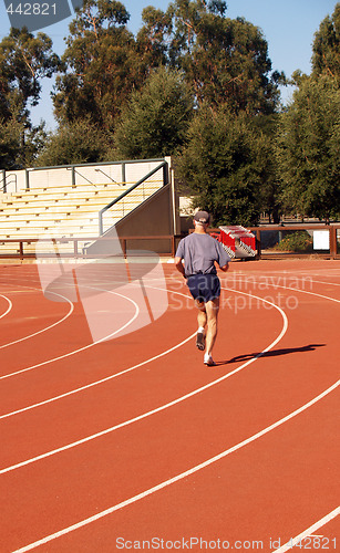 Image of Older man running on curve at track