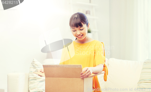 Image of happy asian young woman with parcel box at home