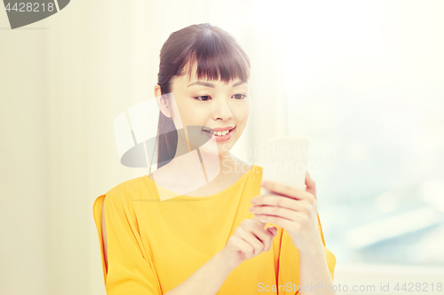 Image of happy asian woman with smartphone at home