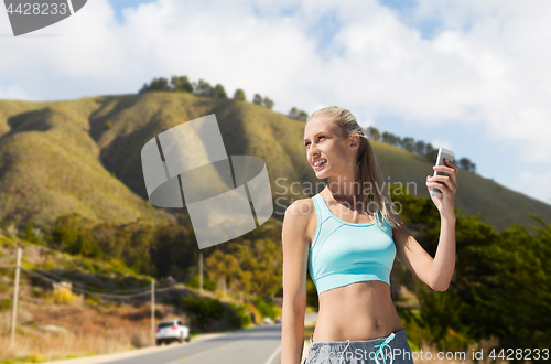 Image of woman with smartphone doing sports over hills