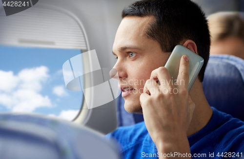 Image of young man calling on smartphone in plane