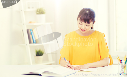 Image of happy asian young woman student learning at home