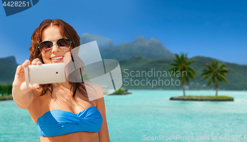 Image of woman taking selfie by smartphone on bora bora
