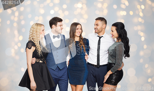 Image of happy friends in party clothes hugging over lights