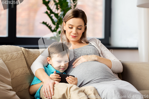Image of pregnant mother and son with smartphone at home