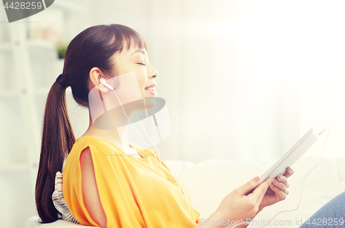 Image of happy asian woman with tablet pc and earphones