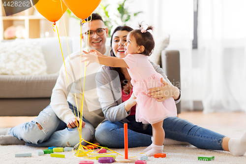 Image of baby girl reaching to balloons at birthday party