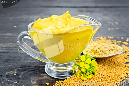 Image of Sauce mustard in sauceboat with powder and flower on black board