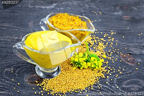 Image of Sauce mustard in two sauceboats with flower on dark board