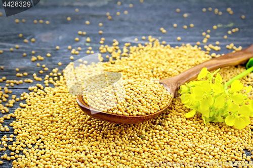 Image of Mustard seeds in spoon with flower on black board